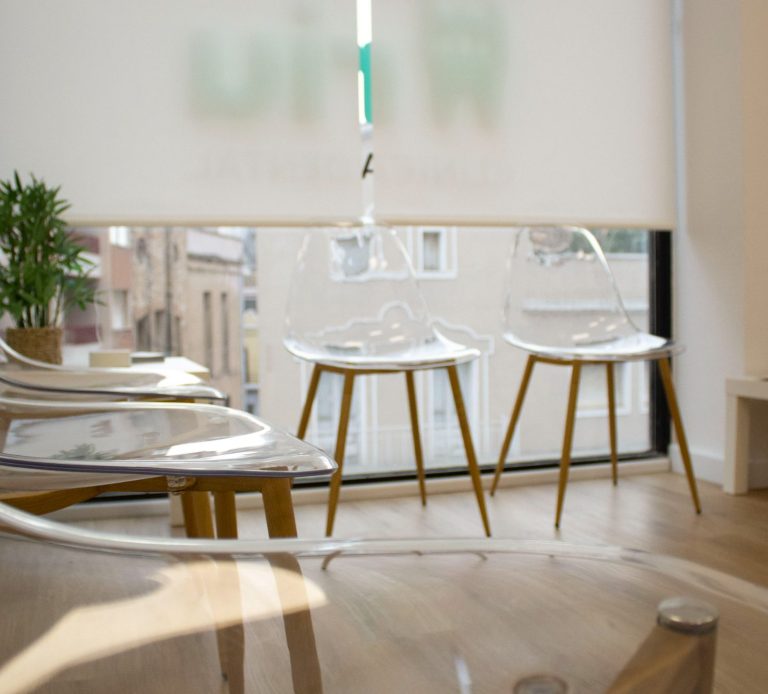 Sillas transparentes de plástico con patas de madera en un ambiente luminoso.